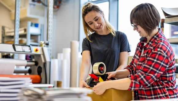 Zwei Frauen beim Einpacken von Versandartikeln.