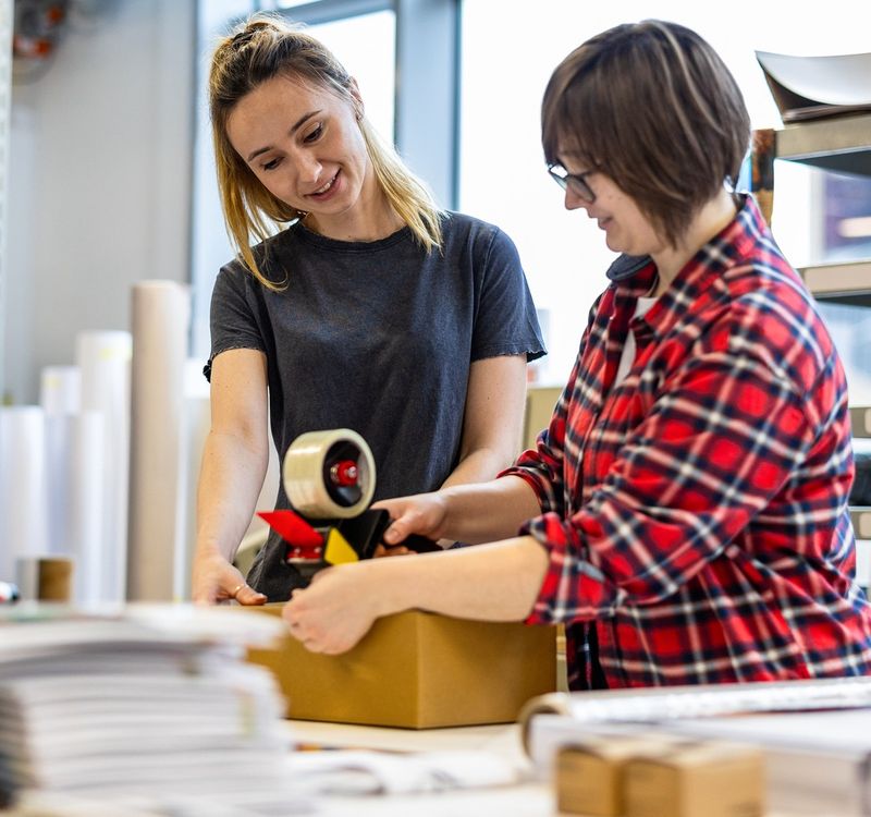 Zwei Frauen beim Einpacken von Versandartikeln.