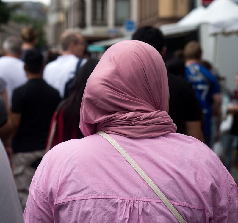 Frau mit Kopftuch in einer Strassenszenerie.