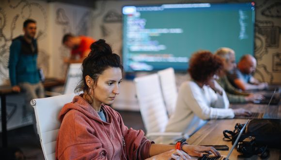 Mehrere Personen arbeiten an Computern in einem Raum.