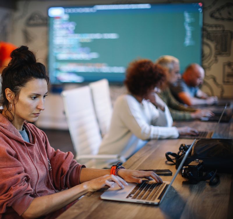 Mehrere Personen arbeiten an Computern in einem Raum.