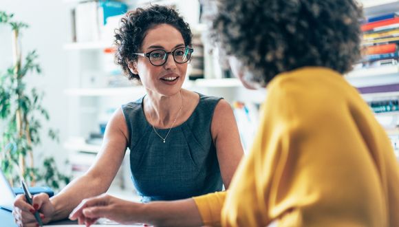 Zwei Frauen sitzen nebeneinander im Gespräch.