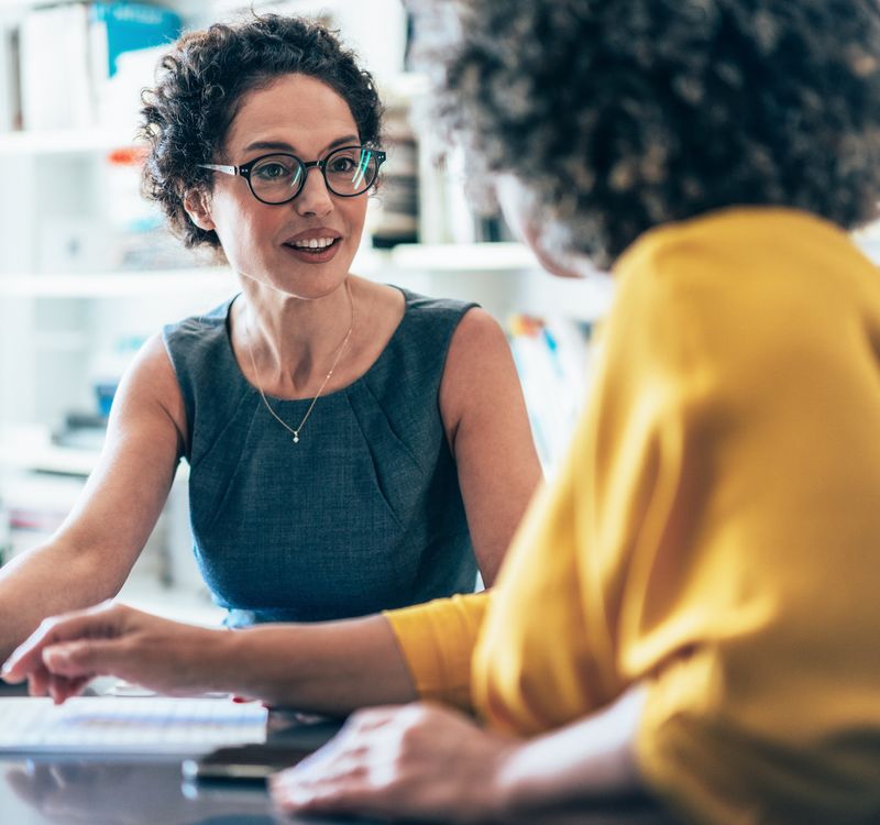 Zwei Frauen sitzen nebeneinander im Gespräch.