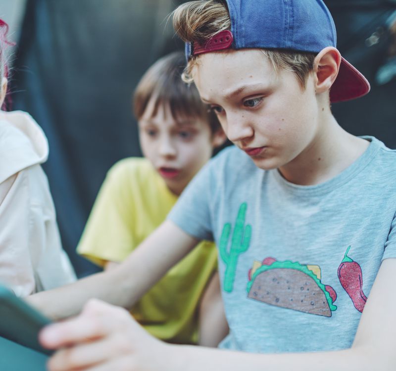 Drei Kinder schauen sich etwas auf einem Tablet an.