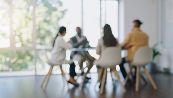 Vier Personen sitzen an einem Bürotisch im Gespräch.
