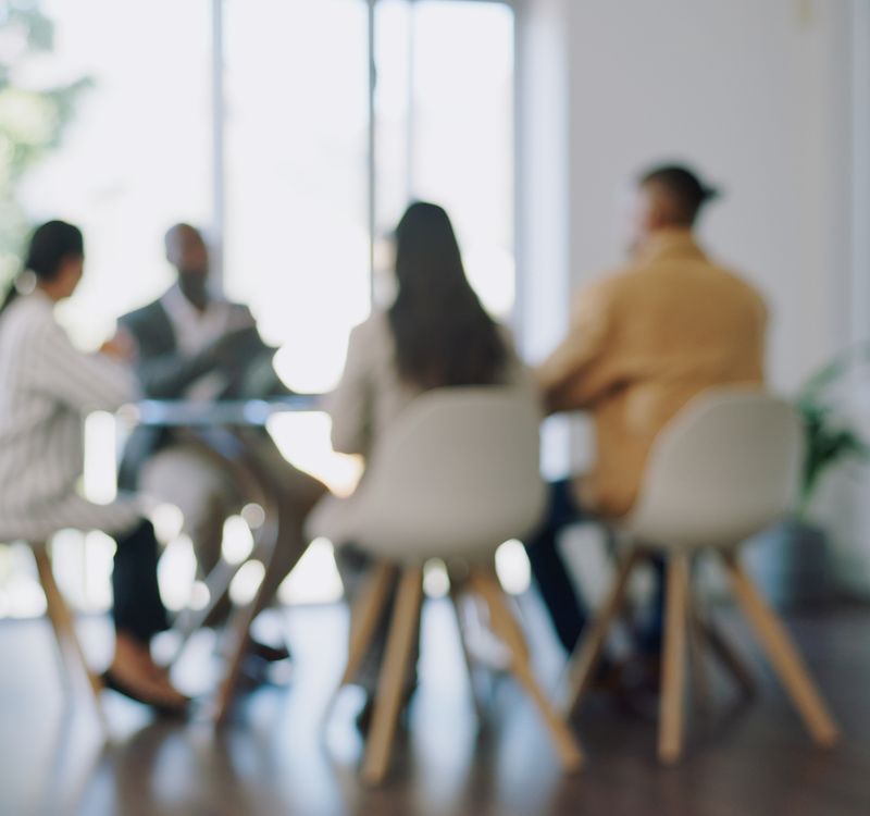 Vier Personen sitzen an einem Bürotisch im Gespräch.