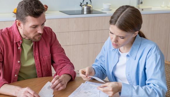 Paar sitzt mit Rechnungen am Küchentisch.
