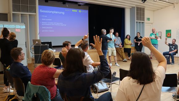Ein Teil der Workshop-Gruppe hält die Hand hoch.