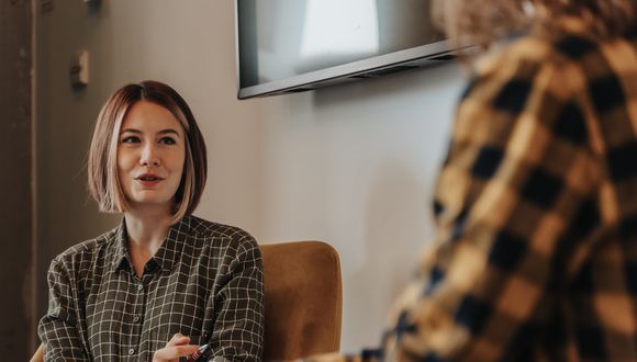 Zwei Frauen sitzen sich im Gespräch gegenüber.