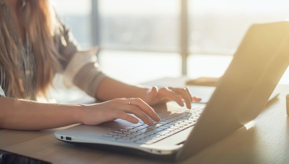 Frau tippt auf einem Laptop.