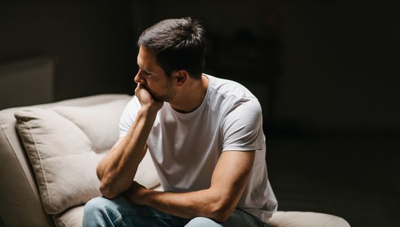Mann sitzt deprimiert auf Sofa.