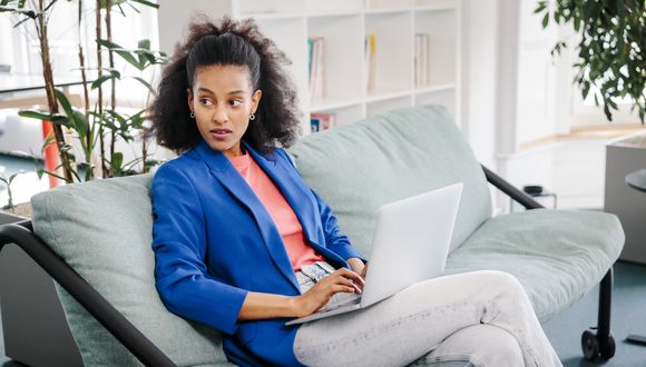 Sozialarbeiterin arbeitet am Laptop auf Sofa