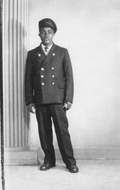 a black and white photograph of a young man of Caribbean heritage wearing a railway uniform