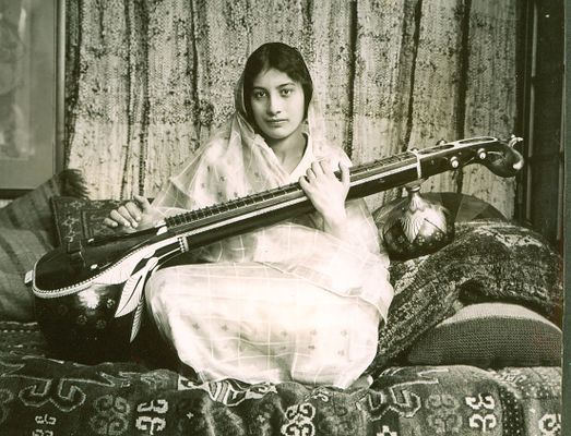 a young woman of Indian hertiage playing a vina, a stringed Indian instument