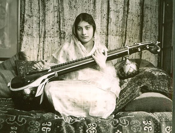 a young woman of Indian hertiage playing a vina, a stringed Indian instument