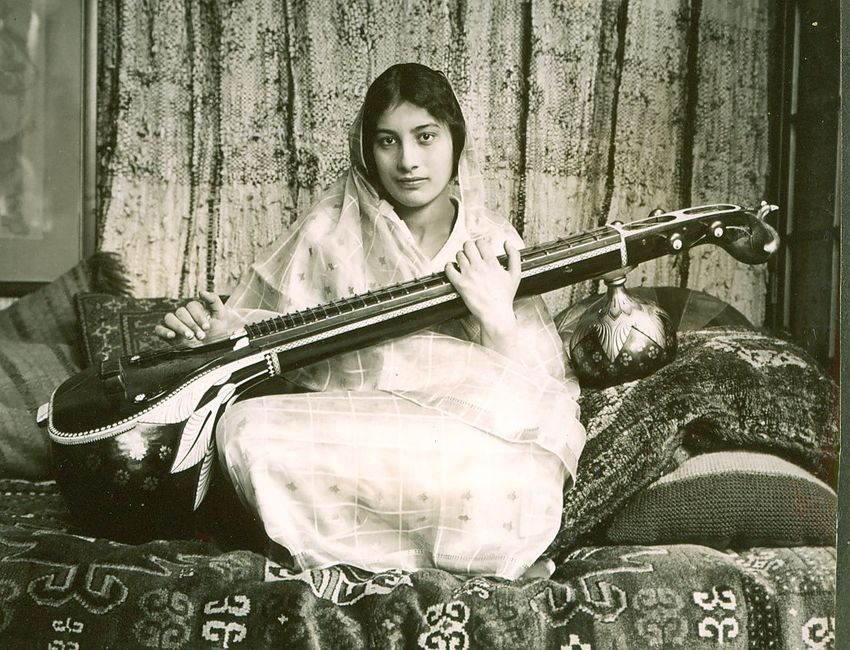a young woman of Indian hertiage playing a vina, a stringed Indian instument