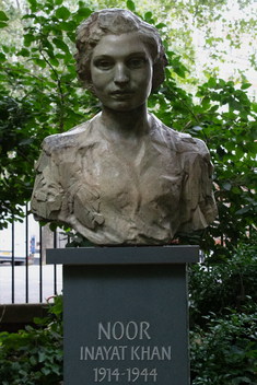 bronze bust of Noor Inayat Khan on black stone plinth surreounded by greenery. Noor Inayat Khan 1914 to 1944 written on the plinth.