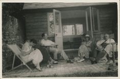 a group of people, including Virgina Woolf, seated in deckchairs outside a writing cabin at Monk's house