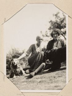 two older white women and a dog sitting on a grass slope