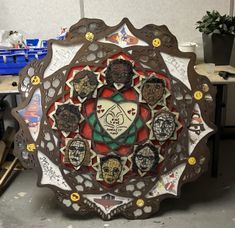Art piece featuring stylized faces on a circular frame with emoticons. Central heart reads "one amongst many." Multicolored background.