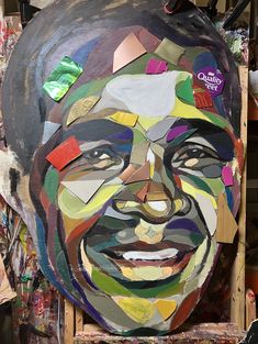 Colorful abstract portrait made from mixed media, using vibrant geometric shapes and candy wrappers, depicting a smiling face on a canvas.
