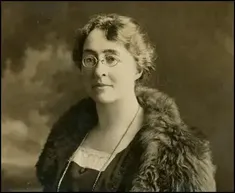 black and white image of a middle aged woman wearing glasses and a fur cape