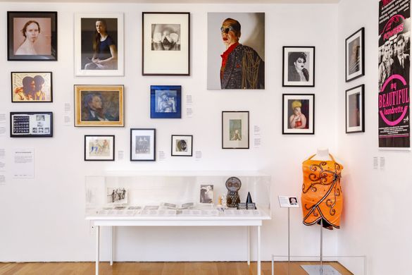 image of exhibition of photos, paintings, posters and objects inside a white gallery space