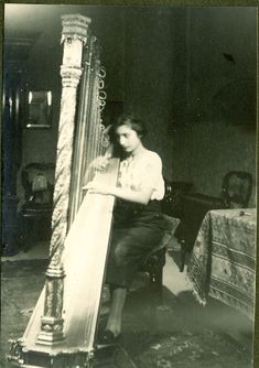 Noor Inayat Kahn, a young woman of Indian heritage playing a harp. She is dressed in a dark coloured skirt and white blouse.