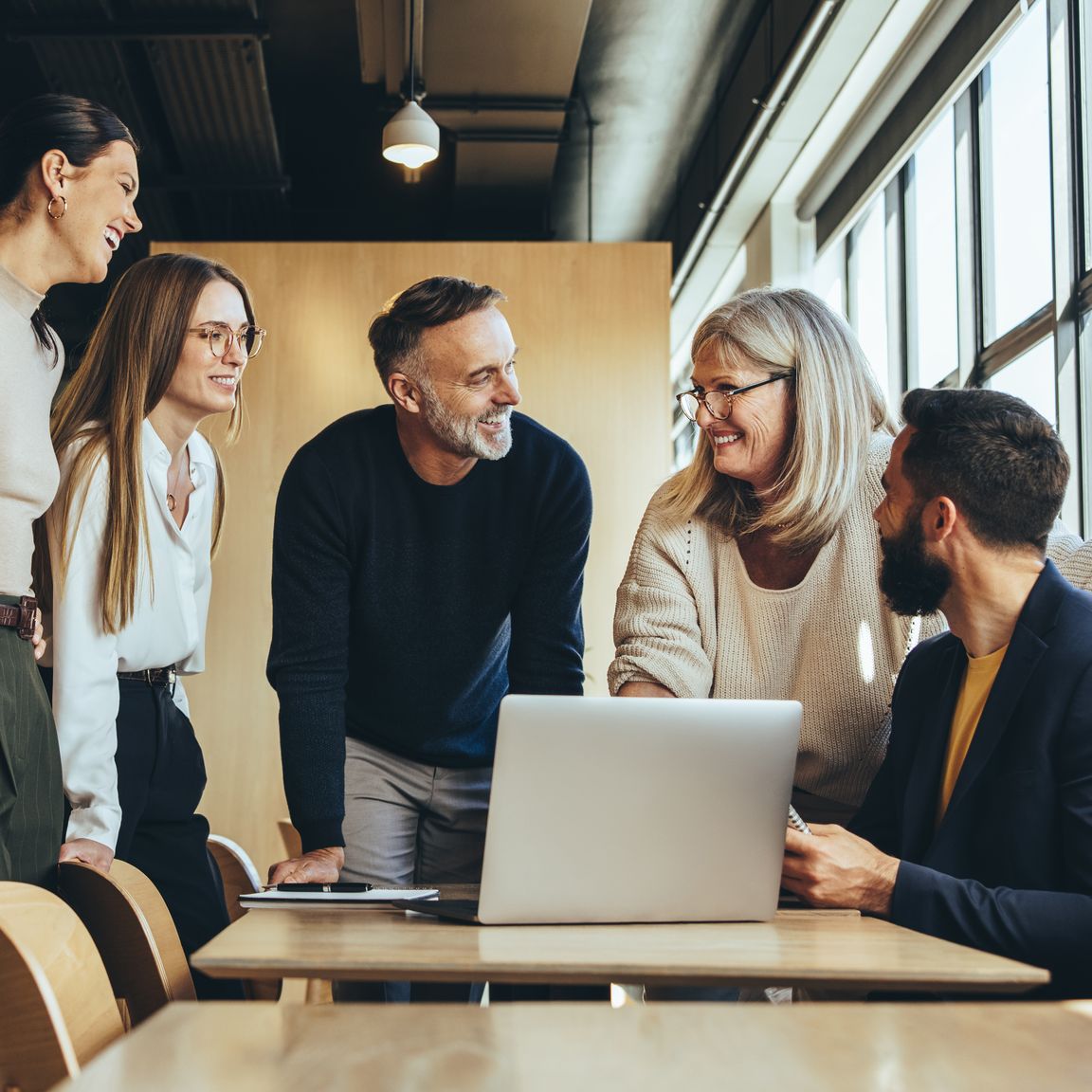 Bank-Verlag - Vielfalt und Chancengleichheit Fünf Mitarbeitende schauen im Meeting auf einen Laptop