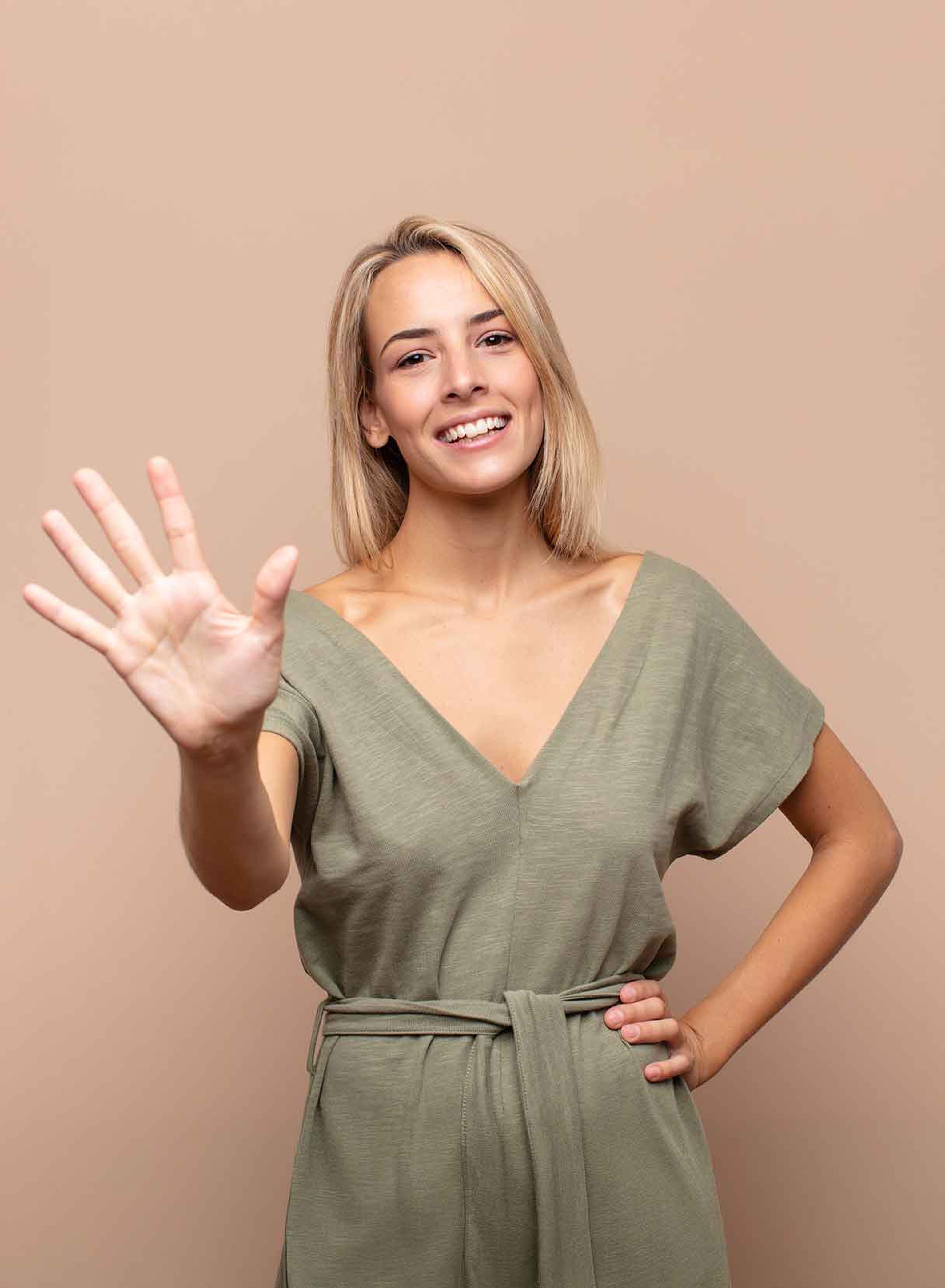 Ragazza bionda sorridente mostra le cinque dita di una mano