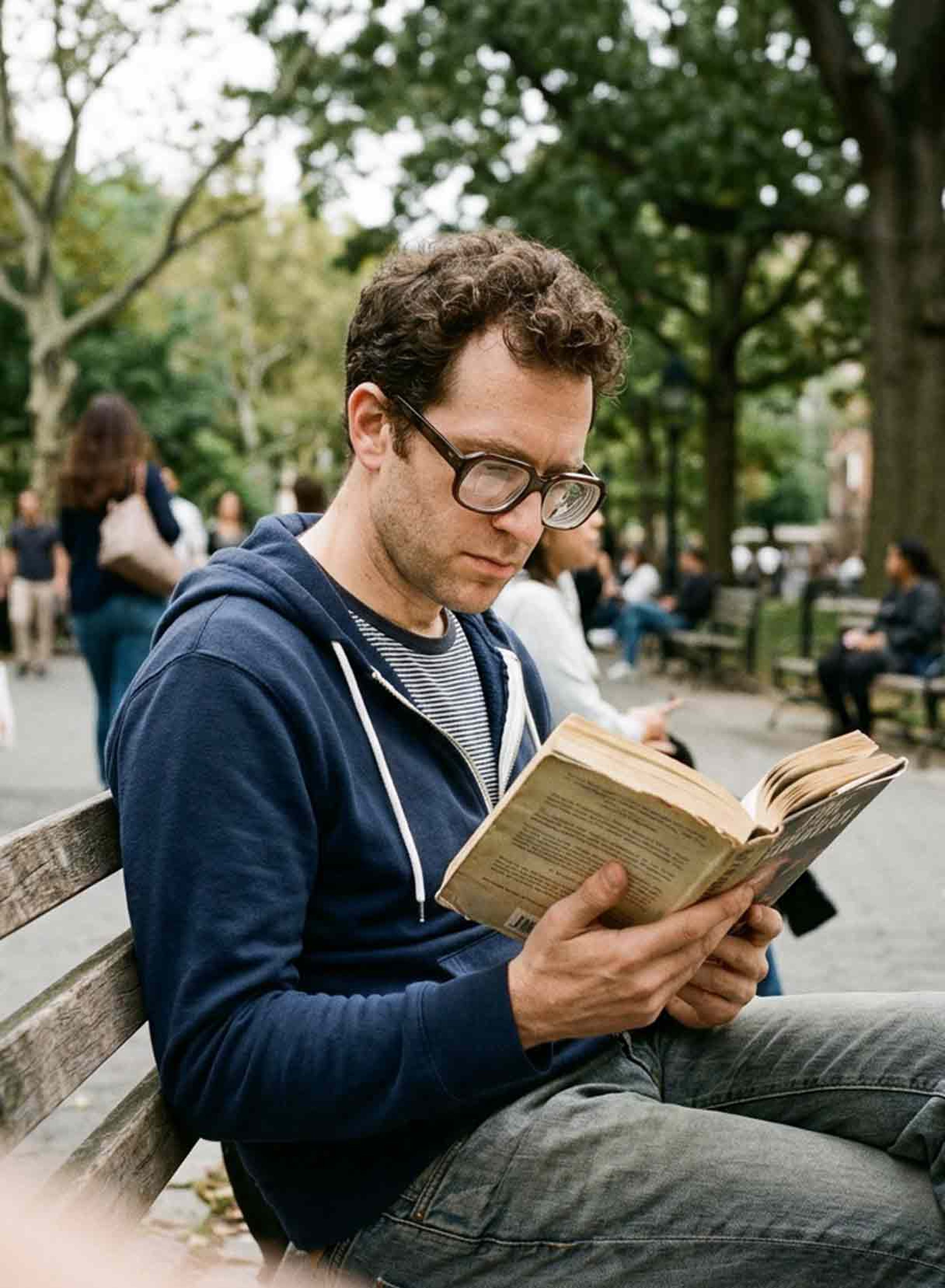 uomo con miopia degenerativa legge un libro su una panchina in un parco pubblico