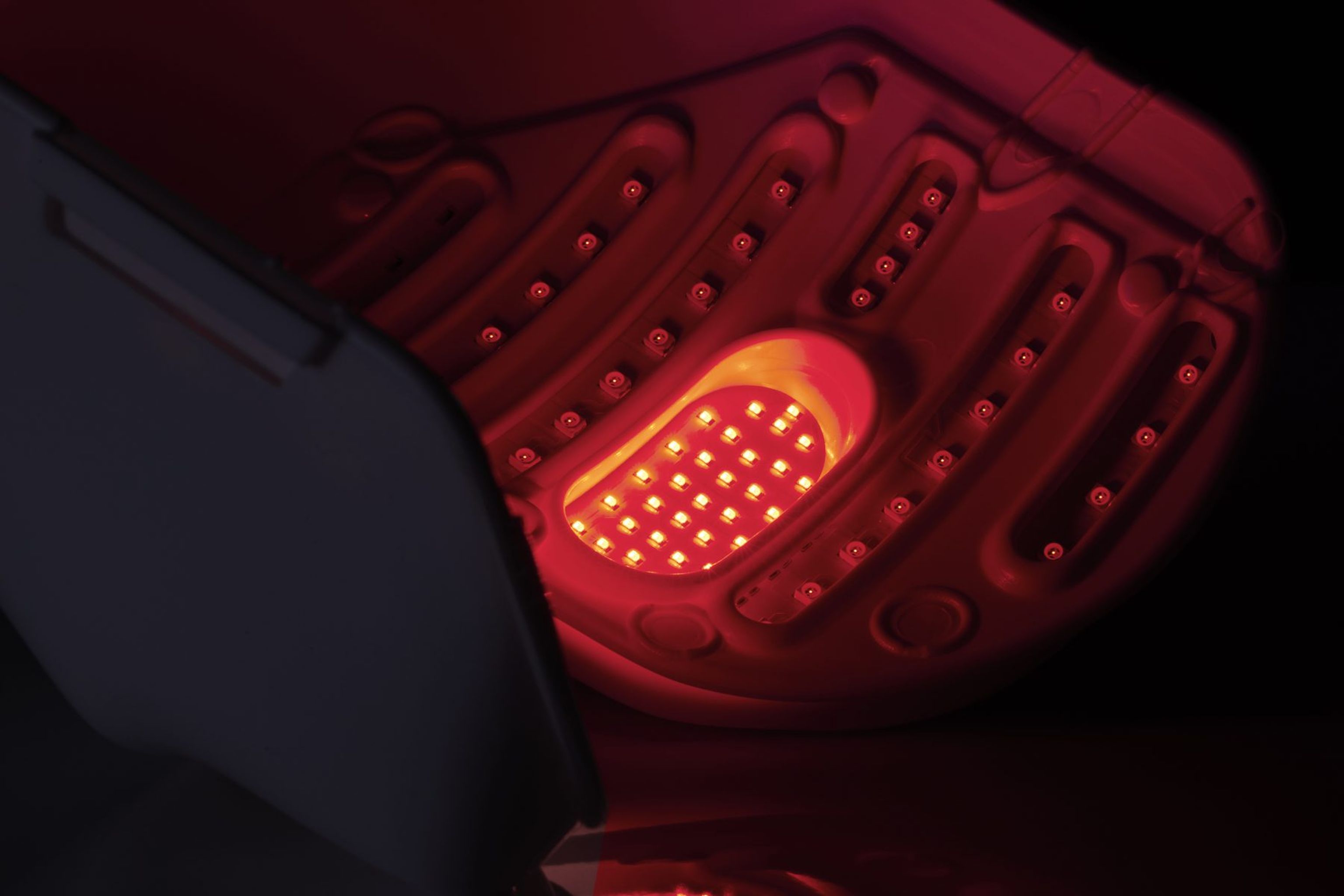 Paziente durante una seduta di fotobiomodulazione con la maschera LM LLLT a luce rossa, a occhi chiusi