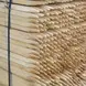 Stacked wooden fence posts with pointed ends, bound together with a black strap, ready for transport or installation.