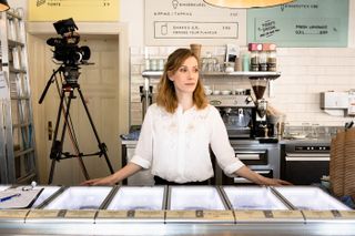 Frau an Café-Theke mit Filmkamera im Hintergrund, minimalistisches Interior Design