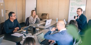 UX/UI-Team in einer Besprechung mit Whiteboard und Laptops