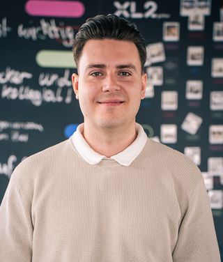 Alexander Schwab vor einer dunklen Wand mit Notizen und Skizzen