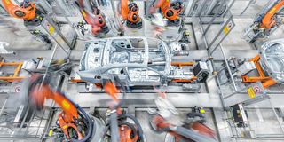 Automobilproduktion mit orangefarbenen Industrierobotern und einem Fahrzeug in der Montage