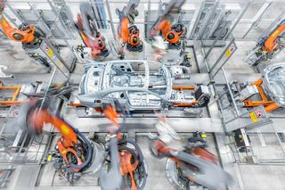 Automobilproduktion mit orangefarbenen Industrierobotern und einem Fahrzeug in der Montage