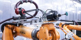 Oranger Industrieroboter mit Schleifwerkzeug in einer Produktionsanlage