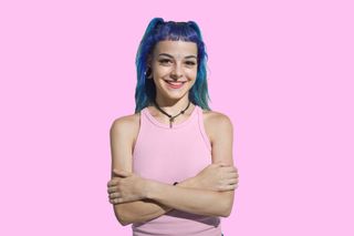 Person with blue hair in front of a pink wall
