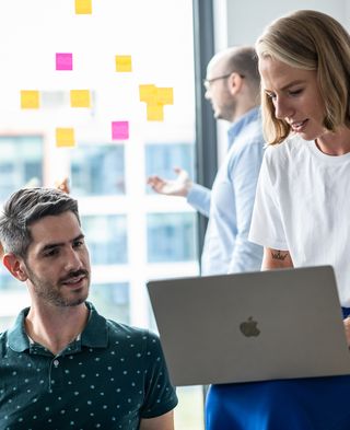 two people sit in the bright room and work together