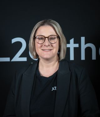 Sabine Blumthaler vor einer schwarzen Wand mit XL2-Schriftzug