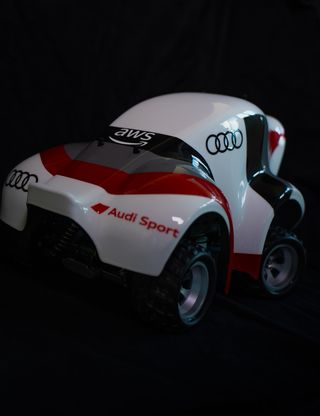 Weiß-rotes Audi Sport Rennfahrzeug mit AWS-Logo vor schwarzem Hintergrund