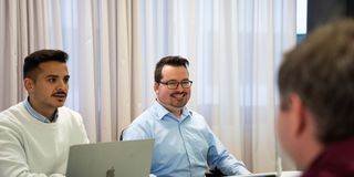Team sitzt in Besprechungsraum vor Laptop