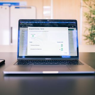 MacBook Pro mit Management-Summary-Anwendung auf dem Bildschirm in einem Büroumfeld