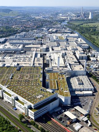 Luftaufnahme eines modernen Fabrikgeländes mit begrünten Dächern, Solaranlagen und umgebender Grünlandschaft