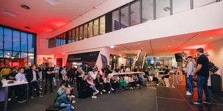 Publikum bei Indoor-Veranstaltung mit roter Beleuchtung und Bühne