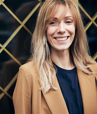 Frau mit Kaffeetasse im modernen Büro führt angeregtes Gespräch, moderne Wanddeko und Obst sichtbar