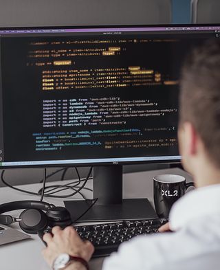 person sits in front of the computer and programs with aws