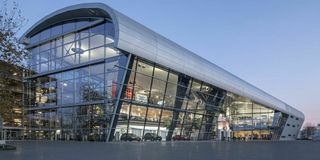 Modernes Gebäude mit geschwungener Glasfassade und innovativem Architekturdesign bei Abenddämmerung